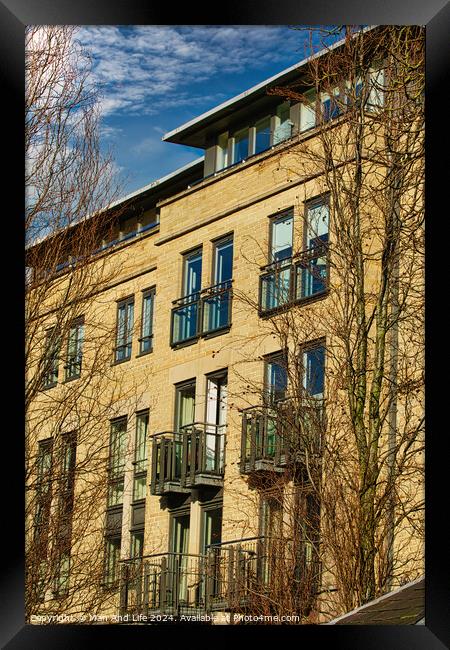 Facade of a modern apartment building with balconies, framed by leafless trees against a clear blue sky in Harrogate, England. Framed Print by Man And Life
