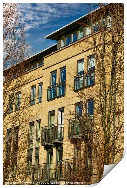 Facade of a modern apartment building with balconies, framed by leafless trees against a clear blue sky in Harrogate, England. Print by Man And Life