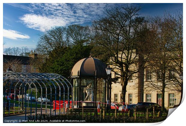 Urban park scene with modern glass pavilion, traditional street lamp, and lush trees under a blue sky with wispy clouds in Harrogate, England. Print by Man And Life