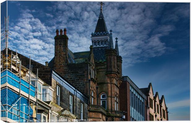 Historic architecture with a spire against a dramatic sky, flanked by modern buildings and scaffolding in Harrogate, England. Canvas Print by Man And Life