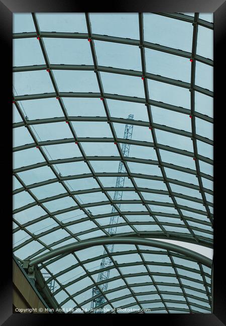 Abstract view of a glass ceiling with a metal frame, showcasing geometric patterns and a clear blue sky in the background. Framed Print by Man And Life