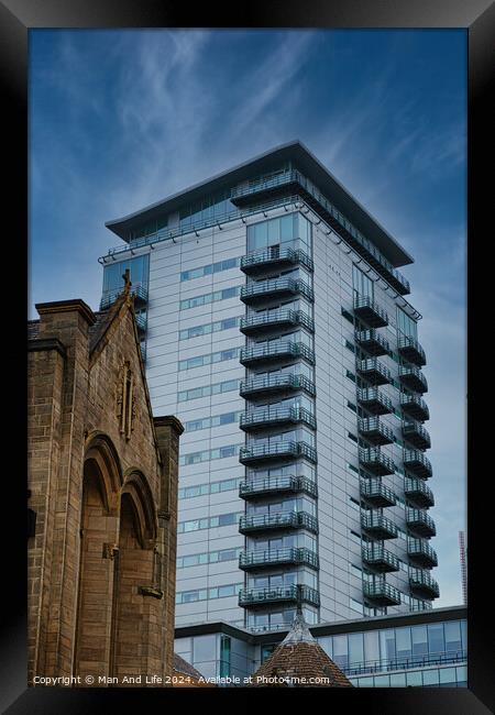 Contrast of old and new architecture with a modern glass skyscraper towering behind a traditional stone church under a clear blue sky in Leeds, UK. Framed Print by Man And Life