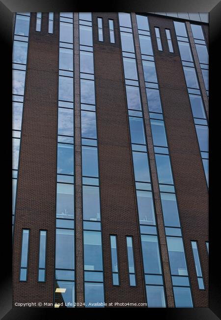 Modern building facade with a pattern of windows and brickwork against a blue sky in Leeds, UK. Framed Print by Man And Life