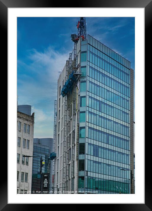 Modern glass building facade with reflections under a cloudy sky, surrounded by urban architecture in Leeds, UK. Framed Mounted Print by Man And Life