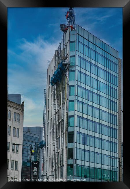 Modern glass building facade with reflections under a cloudy sky, surrounded by urban architecture in Leeds, UK. Framed Print by Man And Life