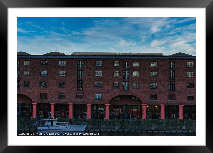 Brick warehouse with arched supports by a canal with a moored boat under a clear blue sky in Liverpool, UK. Framed Mounted Print by Man And Life