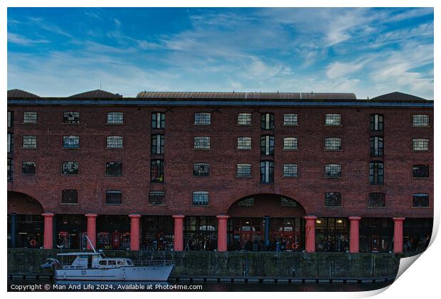 Brick warehouse with arched supports by a canal with a moored boat under a clear blue sky in Liverpool, UK. Print by Man And Life