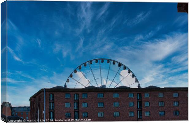 Ferris wheel silhouette against a blue sky with wispy clouds, framed by buildings in Liverpool, UK. Canvas Print by Man And Life