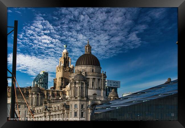 Liverpool's iconic waterfront buildings under a blue sky with wispy clouds. Framed Print by Man And Life