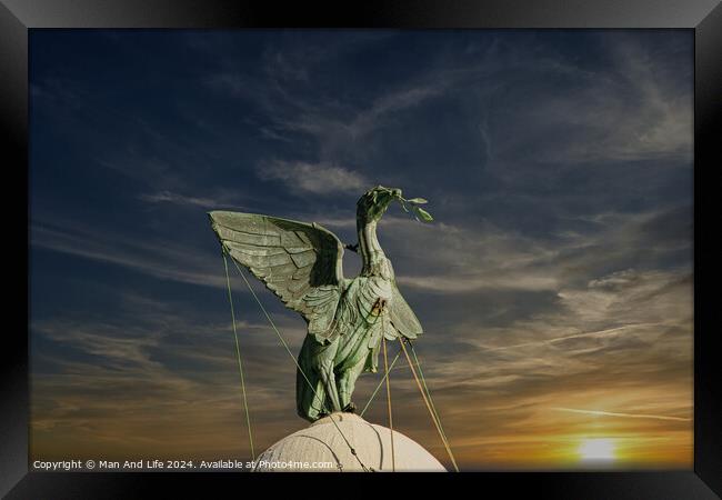 Bronze statue of an angel with outstretched wings against a vibrant sunset sky in Liverpool, UK. Framed Print by Man And Life