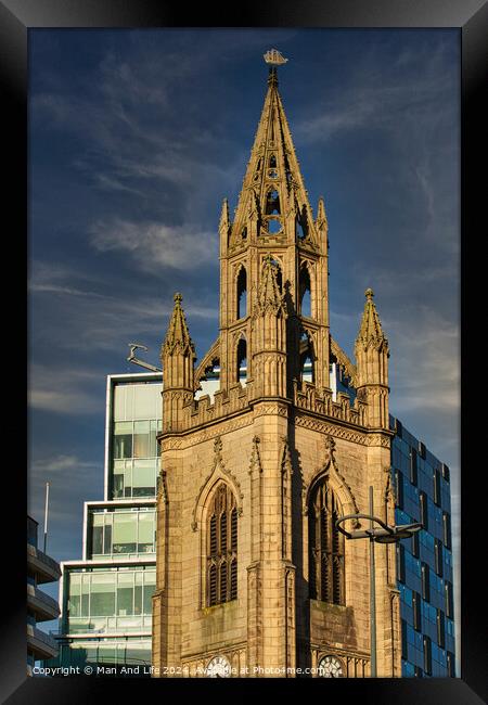Gothic church spire against a blue sky with modern buildings in the background in Liverpool, UK. Framed Print by Man And Life