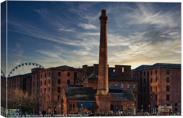 Historic red brick buildings with tall chimney against a dramatic sunset sky, with a Ferris wheel in the background in Liverpool, UK. Canvas Print by Man And Life