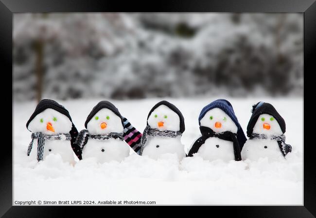 Cute little snowmen dressed in hats and scarfs in snow Framed Print by Simon Bratt LRPS