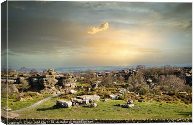 Picturesque rural landscape at sunset with rocky formations and green fields under a cloudy sky at Brimham Rocks, in North Yorkshire Canvas Print by Man And Life
