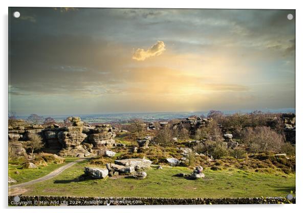 Picturesque rural landscape at sunset with rocky formations and green fields under a cloudy sky at Brimham Rocks, in North Yorkshire Acrylic by Man And Life