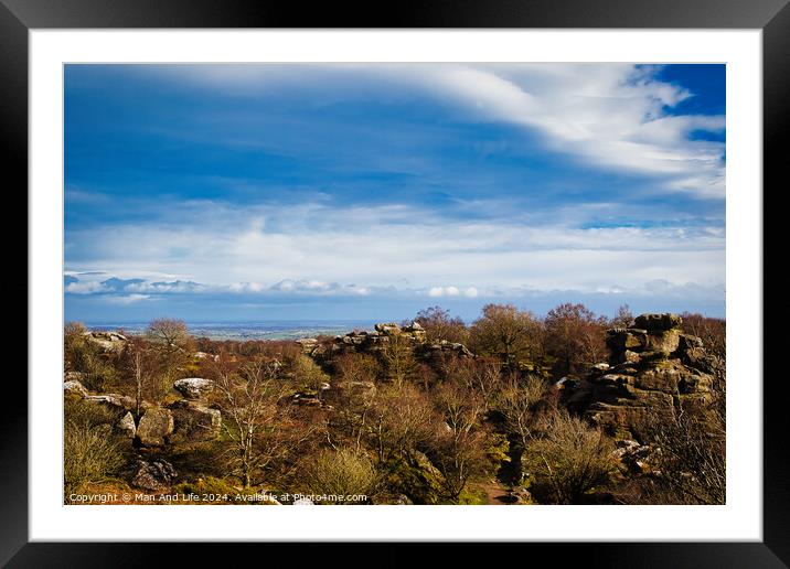 Scenic view of rocky terrain with lush greenery under a blue sky with fluffy clouds, overlooking a distant body of water at Brimham Rocks, in North Yorkshire Framed Mounted Print by Man And Life