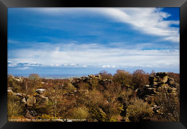 Scenic view of rocky terrain with lush greenery under a blue sky with fluffy clouds, overlooking a distant body of water at Brimham Rocks, in North Yorkshire Framed Print by Man And Life