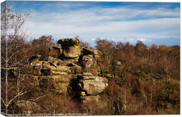 Rocky landscape with boulders and sparse vegetation under a cloudy sky at Brimham Rocks, in North Yorkshire Canvas Print by Man And Life