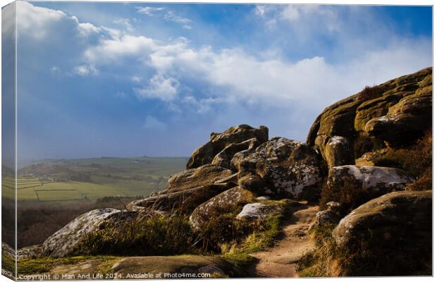 Majestic rocky landscape with sunlit grass under a blue sky with clouds at Brimham Rocks, in North Yorkshire Canvas Print by Man And Life