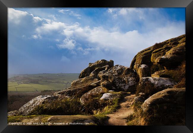 Majestic rocky landscape with sunlit grass under a blue sky with clouds at Brimham Rocks, in North Yorkshire Framed Print by Man And Life