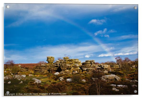 Vibrant rainbow over a rocky landscape with scattered boulders and lush greenery under a blue sky with clouds at Brimham Rocks, in North Yorkshire Acrylic by Man And Life