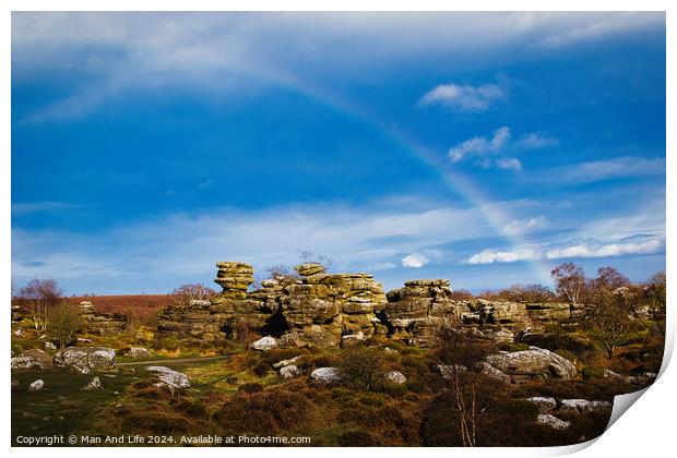 Vibrant rainbow over a rocky landscape with scattered boulders and lush greenery under a blue sky with clouds at Brimham Rocks, in North Yorkshire Print by Man And Life