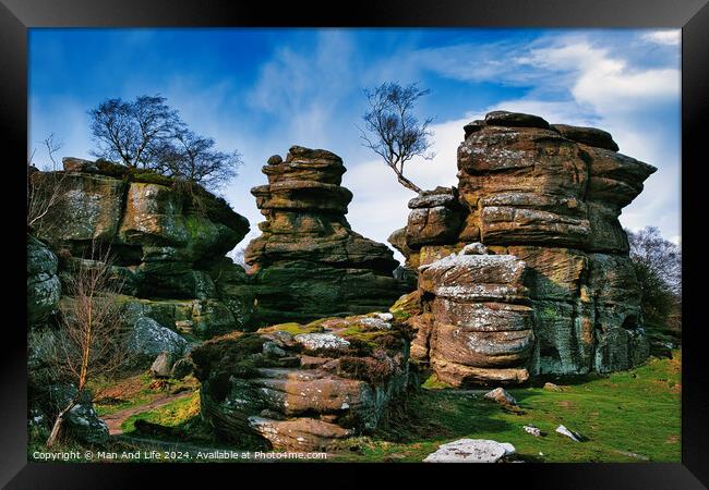 Scenic view of weathered rock formations with a solitary tree against a blue sky with clouds at Brimham Rocks, in North Yorkshire Framed Print by Man And Life