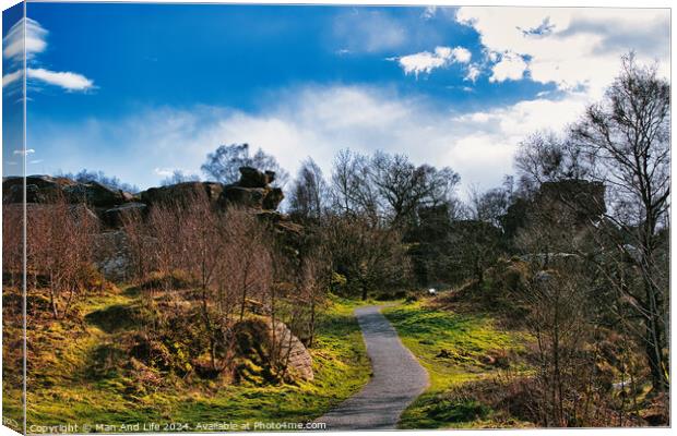 Scenic pathway through a lush park with rocky outcrops and vibrant blue sky with fluffy clouds at Brimham Rocks, in North Yorkshire Canvas Print by Man And Life