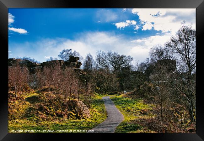 Scenic pathway through a lush park with rocky outcrops and vibrant blue sky with fluffy clouds at Brimham Rocks, in North Yorkshire Framed Print by Man And Life