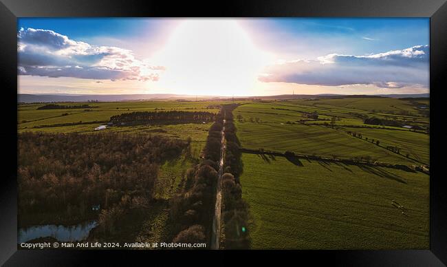 Aerial view of a scenic country road at sunset with lush green fields and a dramatic sky in North Yorkshire. Framed Print by Man And Life