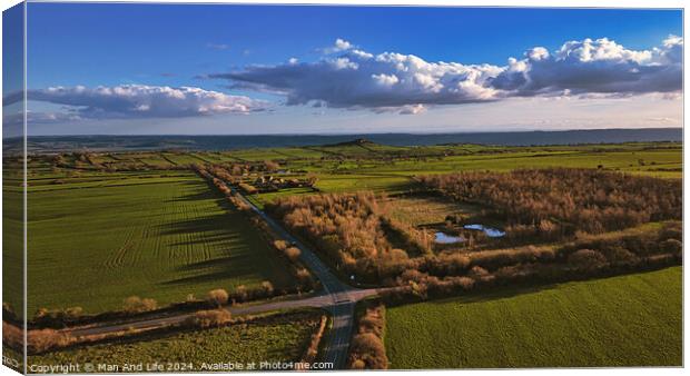 Aerial view of lush countryside with green fields, trees, and a small pond under a blue sky with fluffy clouds in North Yorkshire. Canvas Print by Man And Life
