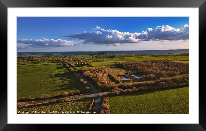 Aerial view of lush countryside with green fields, trees, and a small pond under a blue sky with fluffy clouds in North Yorkshire. Framed Mounted Print by Man And Life