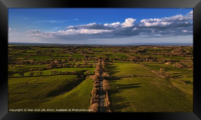 Aerial view of a lush green countryside with a road cutting through, under a vast blue sky with scattered clouds in North Yorkshire. Framed Print by Man And Life