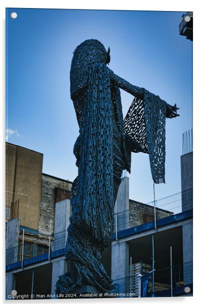 Artistic metal sculpture of a humanoid figure against a clear blue sky, with urban buildings in the background in Leeds, UK. Acrylic by Man And Life
