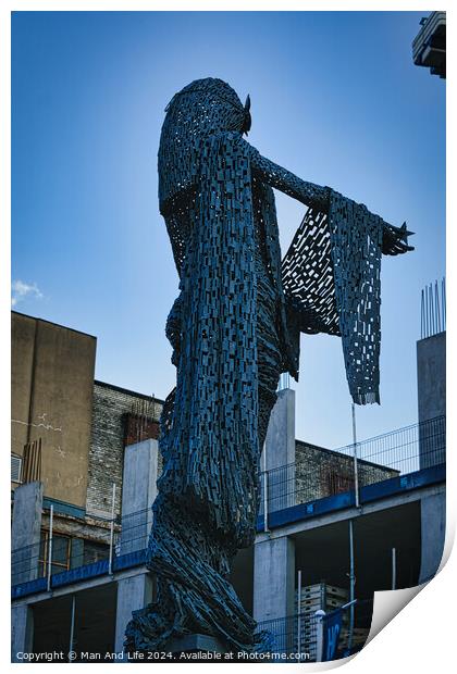 Artistic metal sculpture of a humanoid figure against a clear blue sky, with urban buildings in the background in Leeds, UK. Print by Man And Life