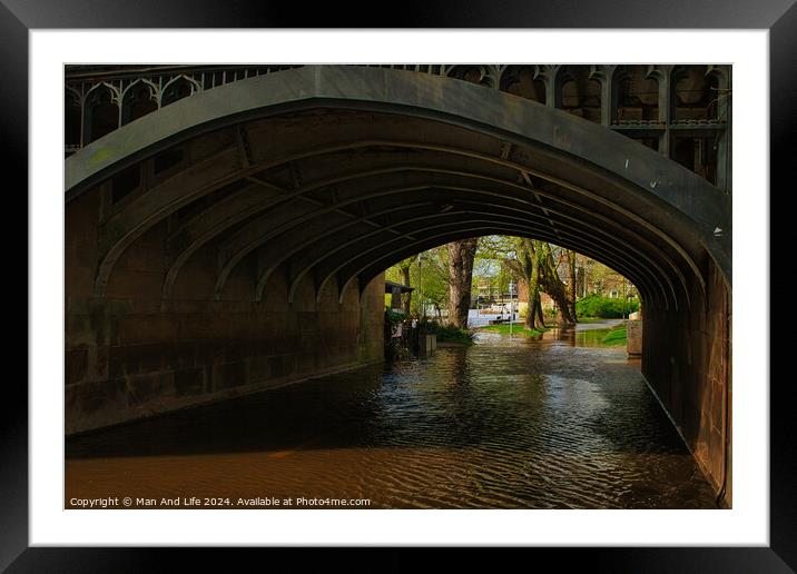 Scenic view under an old stone bridge with intricate arches, reflecting on a tranquil water surface, surrounded by lush greenery in a serene park setting in York, North Yorkshire, England. Framed Mounted Print by Man And Life