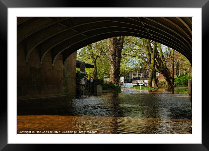 Tranquil river flowing under an arched stone bridge with lush green trees and a hint of urban life in the background, showcasing a blend of nature and city architecture in York, North Yorkshire, England. Framed Mounted Print by Man And Life