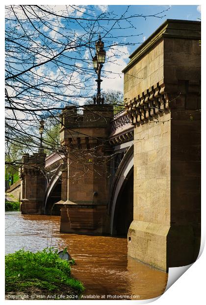 Scenic view of an old stone bridge with arches over a river, framed by blue skies and greenery, with a vintage street lamp adding to the historic charm in York, North Yorkshire, England. Print by Man And Life