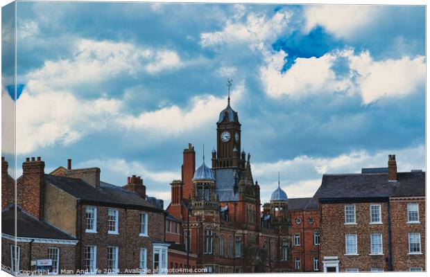 Dramatic clouds loom over a historic town center, featuring a prominent clock tower and classic brick buildings, capturing a quintessential British townscape in York, North Yorkshire, England. Canvas Print by Man And Life