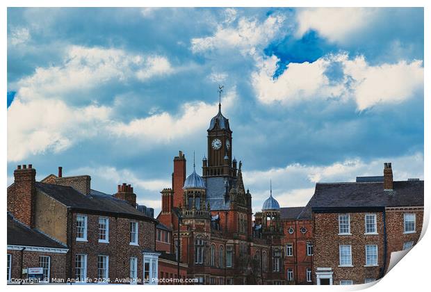 Dramatic clouds loom over a historic town center, featuring a prominent clock tower and classic brick buildings, capturing a quintessential British townscape in York, North Yorkshire, England. Print by Man And Life