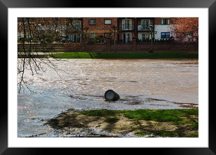 Polluted river with a discarded tire floating on the water's surface, highlighting environmental issues, with urban buildings in the background on a sunny day in York, North Yorkshire, England. Framed Mounted Print by Man And Life
