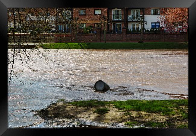 Polluted river with a discarded tire floating on the water's surface, highlighting environmental issues, with urban buildings in the background on a sunny day in York, North Yorkshire, England. Framed Print by Man And Life