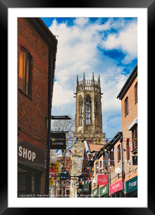 Quaint urban street with festive bunting leading to a historic church tower under a blue sky with fluffy clouds in York, North Yorkshire, England. Framed Mounted Print by Man And Life