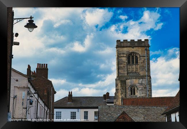 Quaint European street with historic buildings and a prominent church tower under a dramatic sky with fluffy clouds in York, North Yorkshire, England. Framed Print by Man And Life