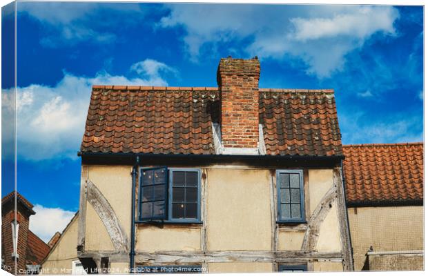 Old European house with half-timbered walls and a red tiled roof against a blue sky with clouds. Vintage architecture with visible wear and character in York, North Yorkshire, England. Canvas Print by Man And Life