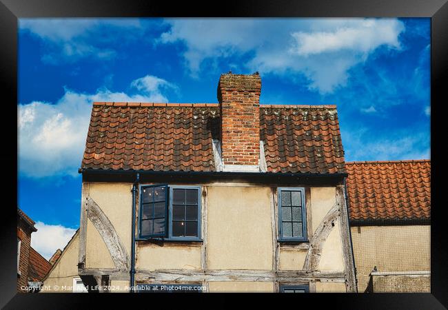 Old European house with half-timbered walls and a red tiled roof against a blue sky with clouds. Vintage architecture with visible wear and character in York, North Yorkshire, England. Framed Print by Man And Life