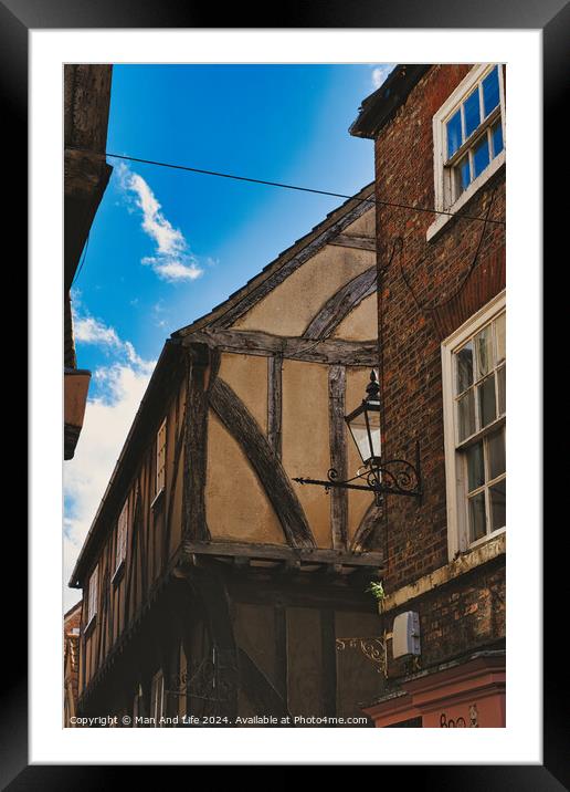 Quaint half-timbered building with exposed wooden beams under a clear blue sky, showcasing traditional architectural details and a vintage street lamp in York, North Yorkshire, England. Framed Mounted Print by Man And Life