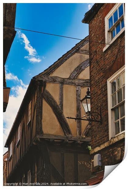 Quaint half-timbered building with exposed wooden beams under a clear blue sky, showcasing traditional architectural details and a vintage street lamp in York, North Yorkshire, England. Print by Man And Life