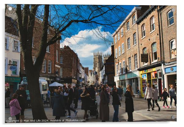 Bustling city street scene with pedestrians, historic buildings, and a cathedral spire under a blue sky with scattered clouds in York, North Yorkshire, England. Acrylic by Man And Life