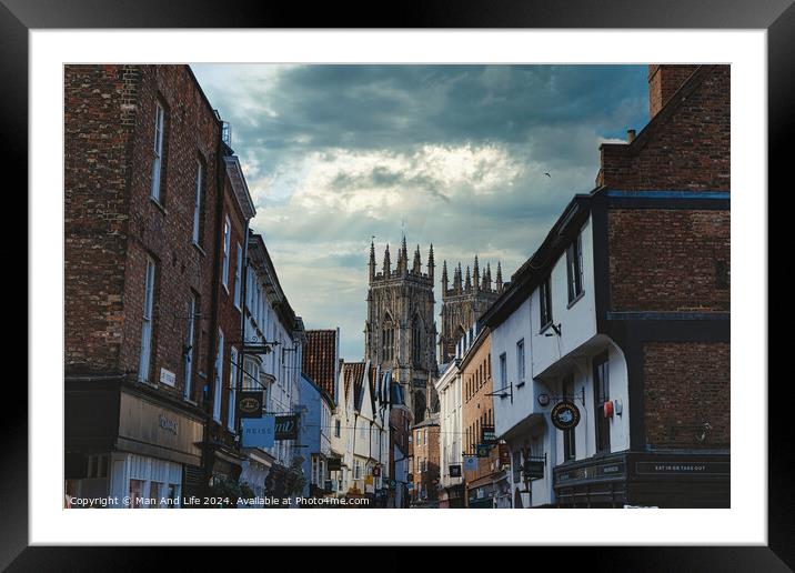 Quaint European street leading to a majestic Gothic cathedral under a dramatic sky at dusk, showcasing historical architecture and urban charm in York, North Yorkshire, England. Framed Mounted Print by Man And Life